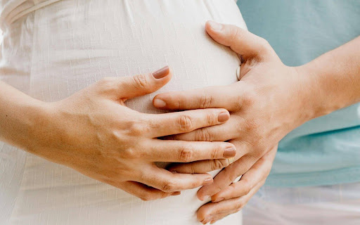 First trimester pregnancy — pregnant woman holding her belly gently.